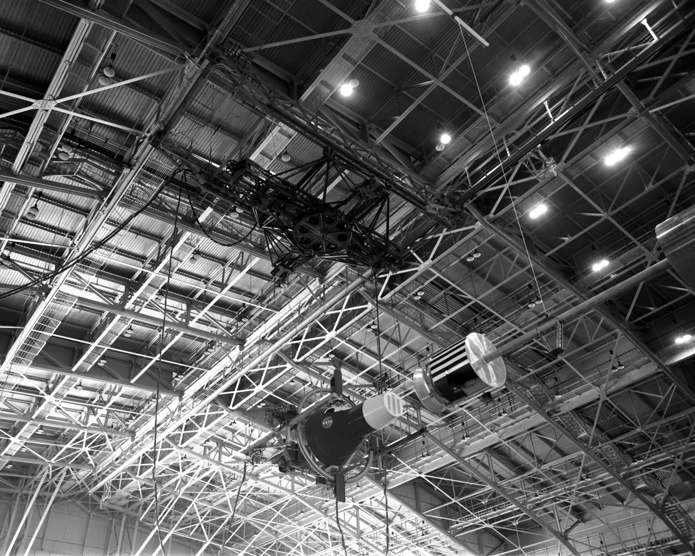 A rendezvous docking simulator hanging from the roof trusses of a large hangar