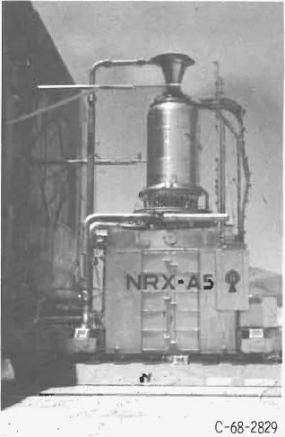 Photograph of the NRX-A5 reactor standing nozzle-up on its test car at an outdoor test stand